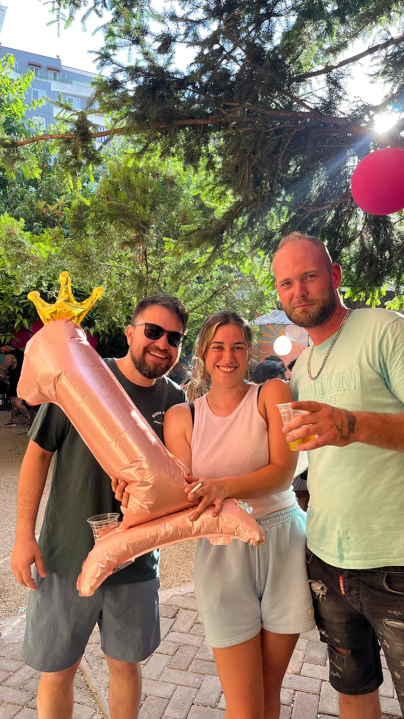 Three friends posing outdoors with a pink number one balloon.